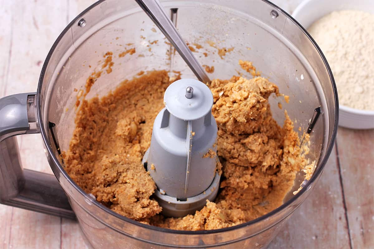 Tempeh burger mixture in a food processor with a spoon.
