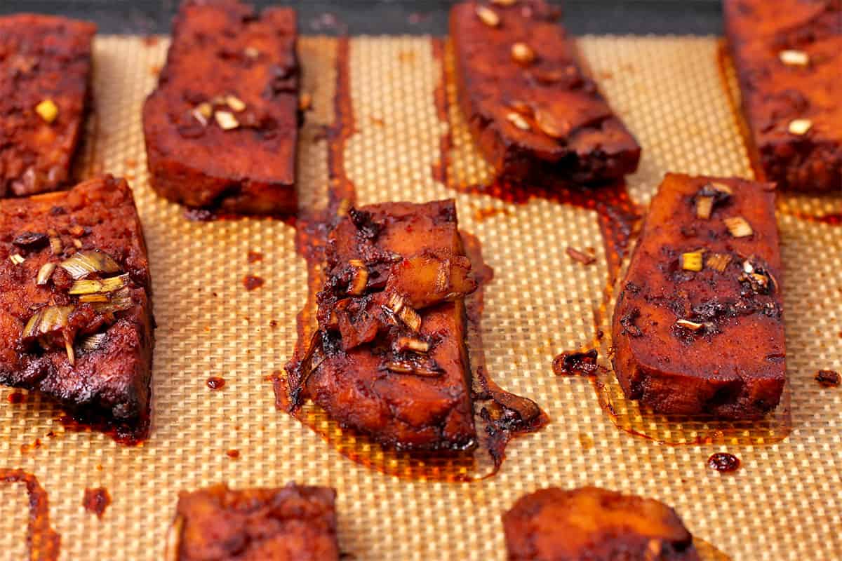 Baked tofu with marinade on a baking mat.