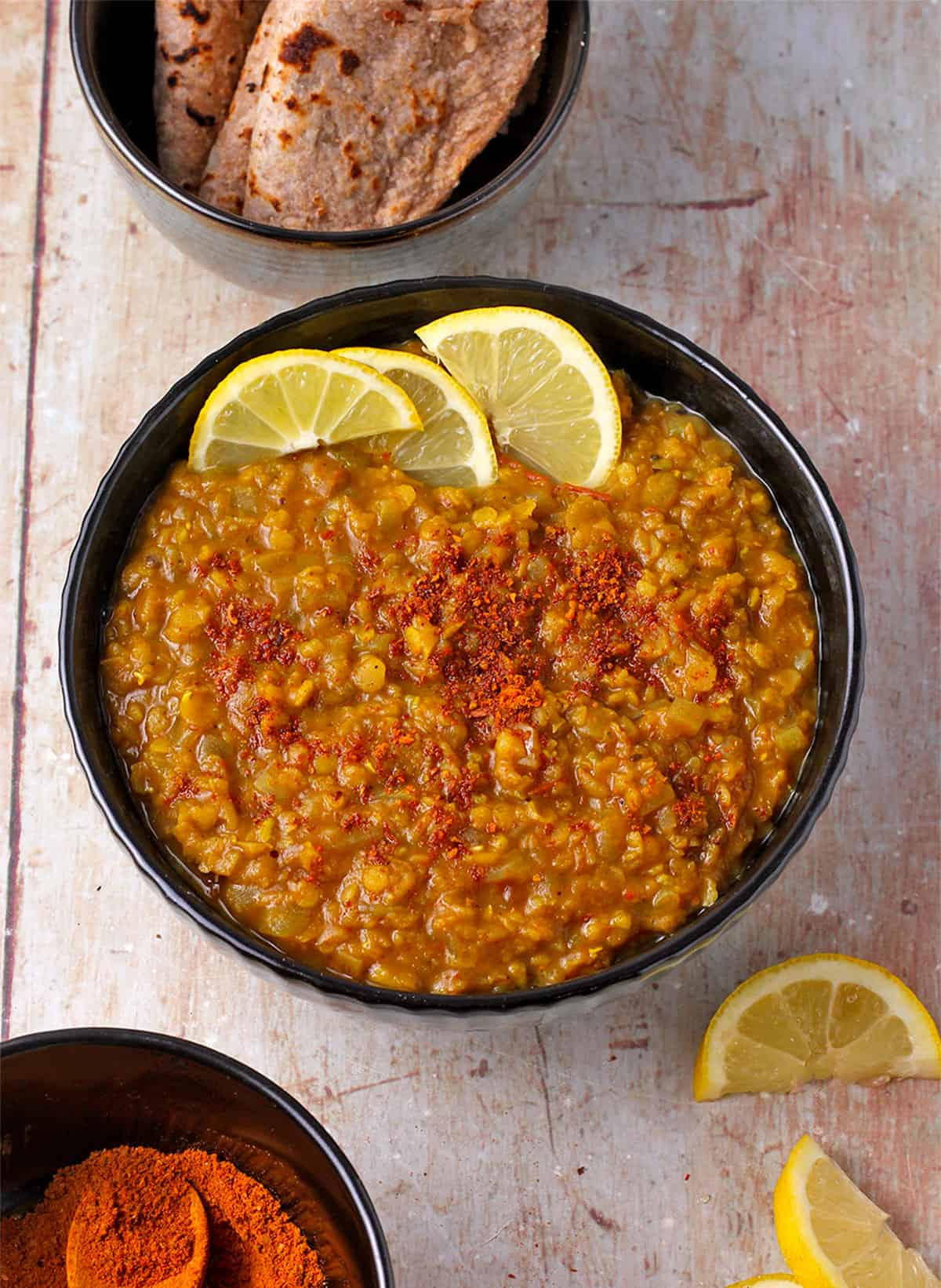 A bowl of Ethiopian red lentils with lemon wedges and another bowl with Berbere spices.