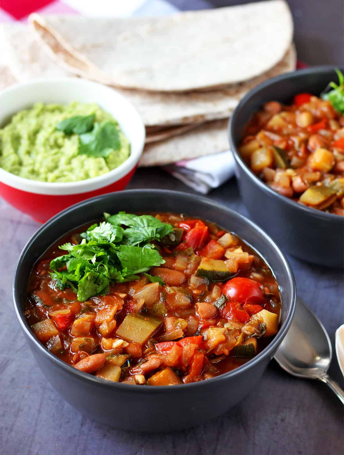 A bowl of zucchini chili with pinto beans and tomatoes with cilantro garnish.