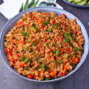 Bulgur pilaf with carrots, zucchini, red pepper, celery, and onions in a blue bowl.