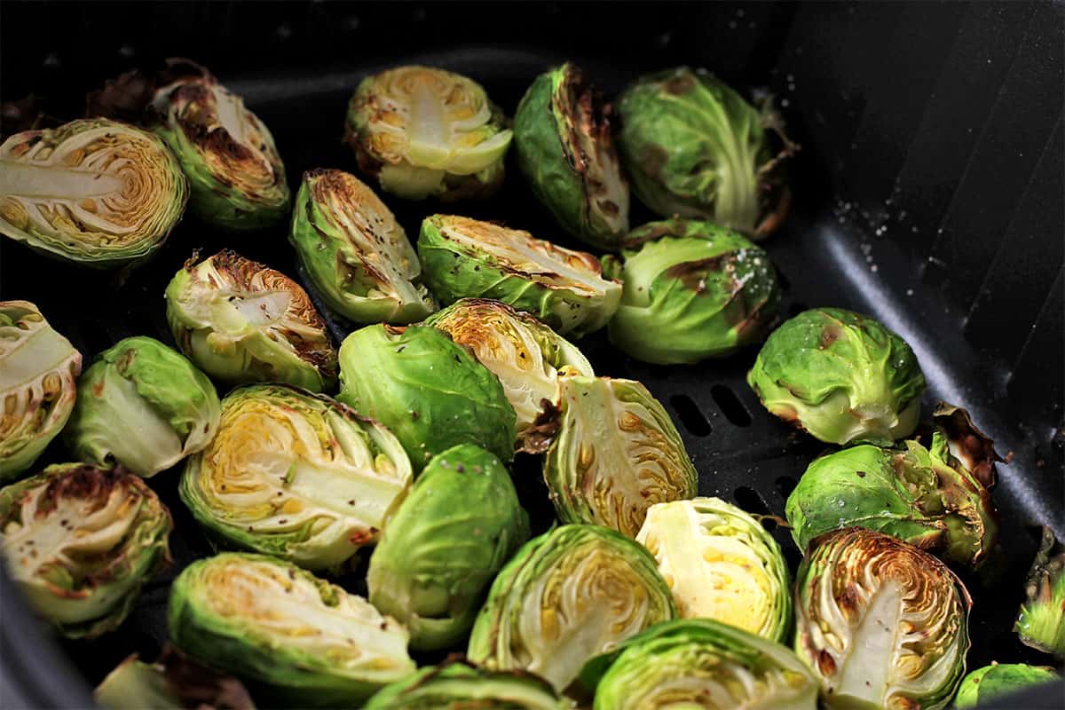 Roasted Brussels sprouts halves in an air fryer basket.