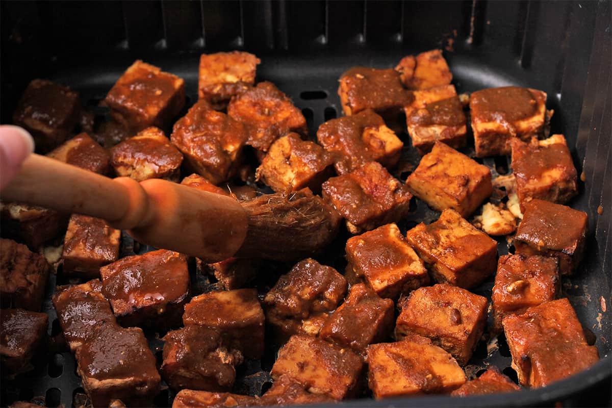 Jerk marinade is brushed over tofu cubes.