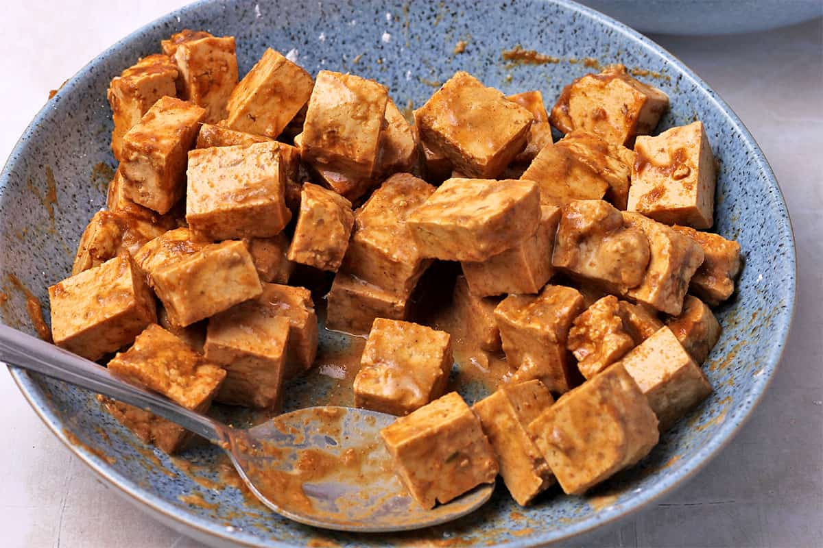 Tofu cubes are mixed with marinade and cornstarch.