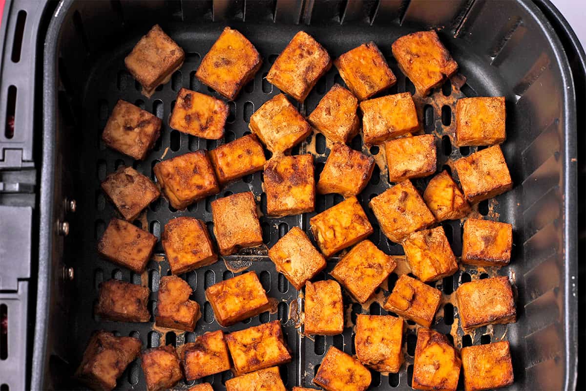 Marinated jerk tofu cubes are cooked in an air fryer.