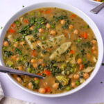 A bowl of vegan dumpling soup with vegetables and chickpeas.