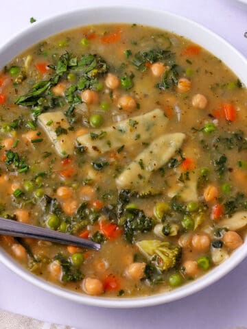 A bowl of vegan dumpling soup with vegetables and chickpeas.