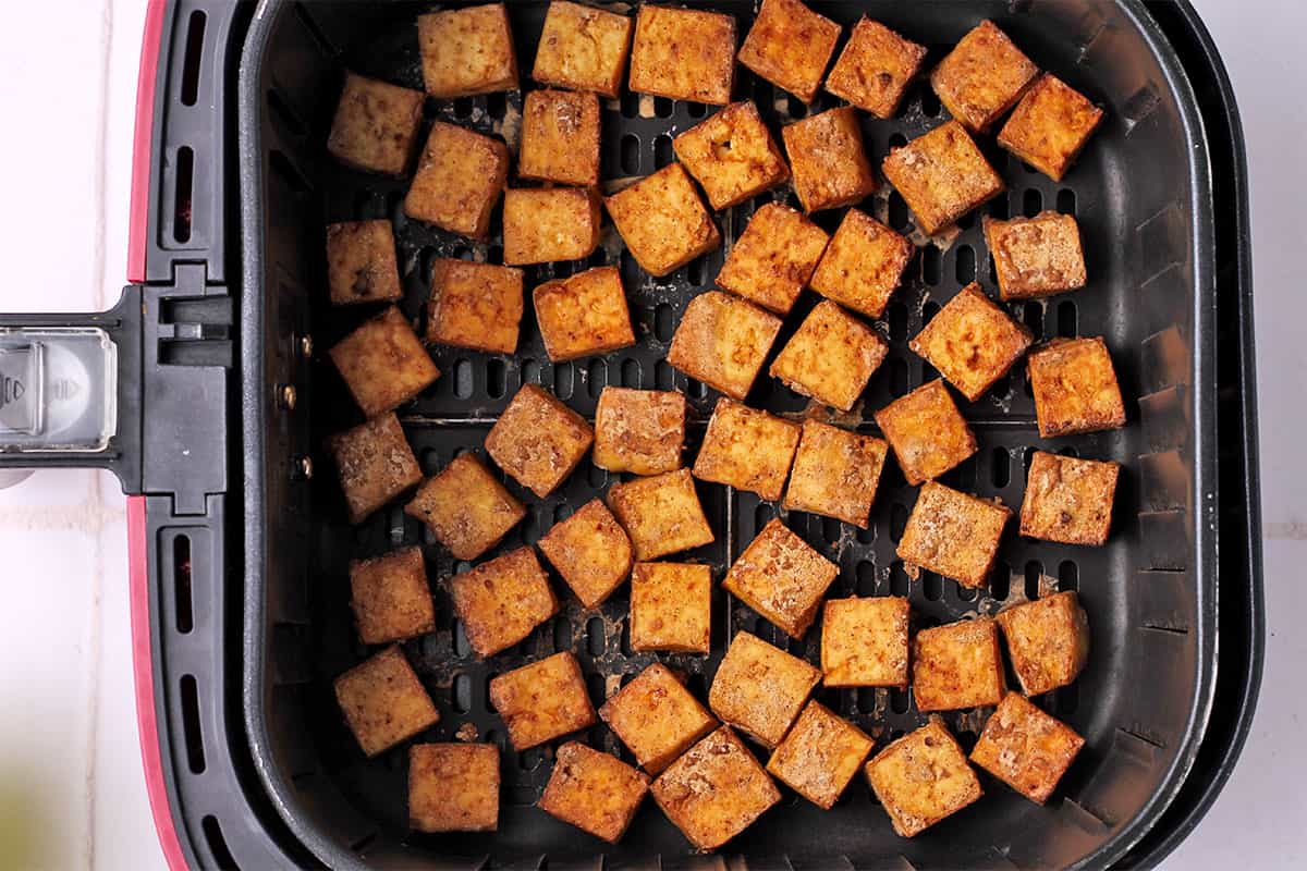Crispy tofu cubes in air fryer basket.