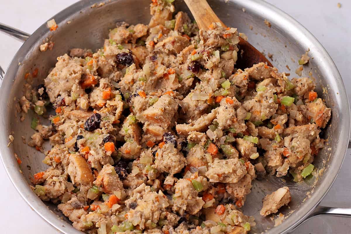 Bread stuffing with carrots, cranberries, and walnuts in a pan.