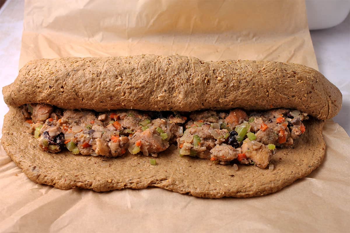 Seitan dough with stuffing inside is rolled into a tube.