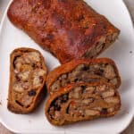 Sliced vegan stuffed seitan roast on a white plate.