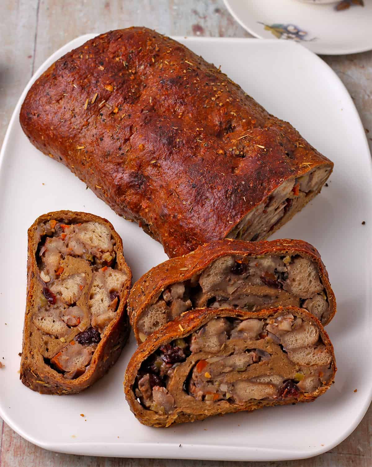 Sliced seitan roast with stuffing on a white plate.