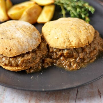 Two split biscuits with lentil gravy on a black plate.