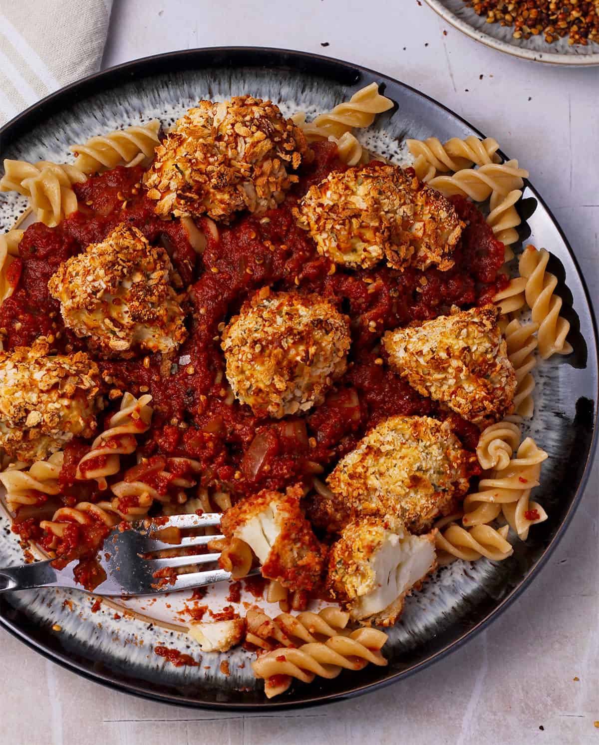 Cauliflower parmesan bites with pasta and tomato sauce on a plate.