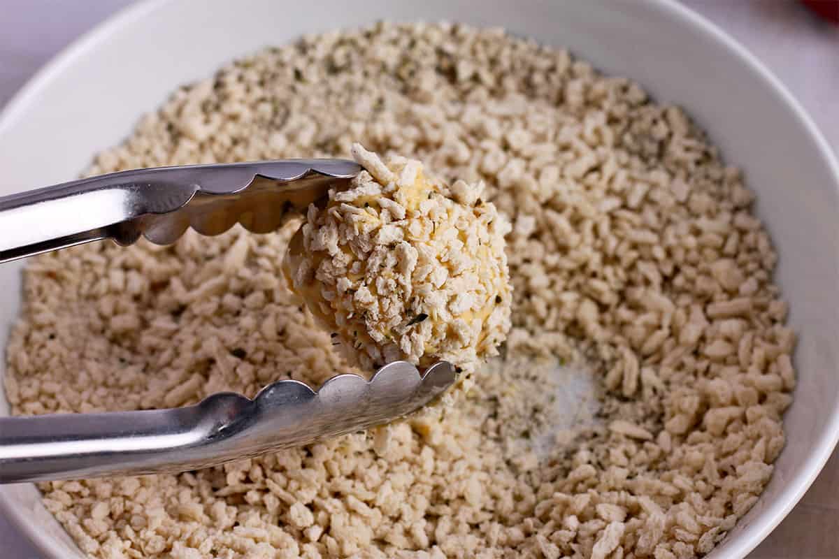 A cauliflower floret is rolled in panko.