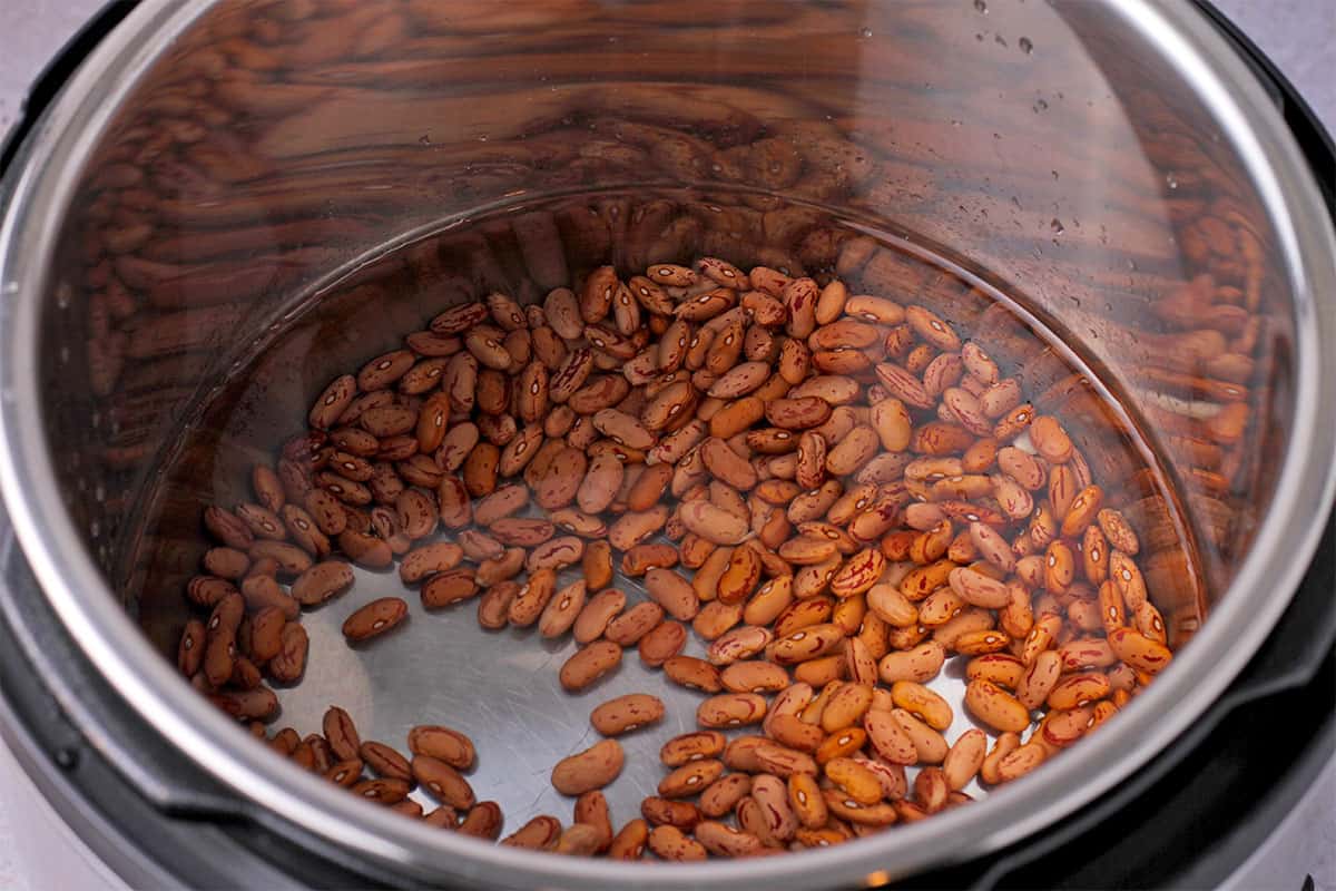 Pinto beans are soaked in water in the Instant Pot.