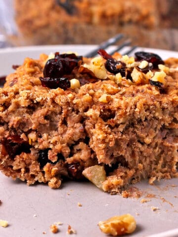 A slice of vegan baked oatmeal with cranberries and walnuts.