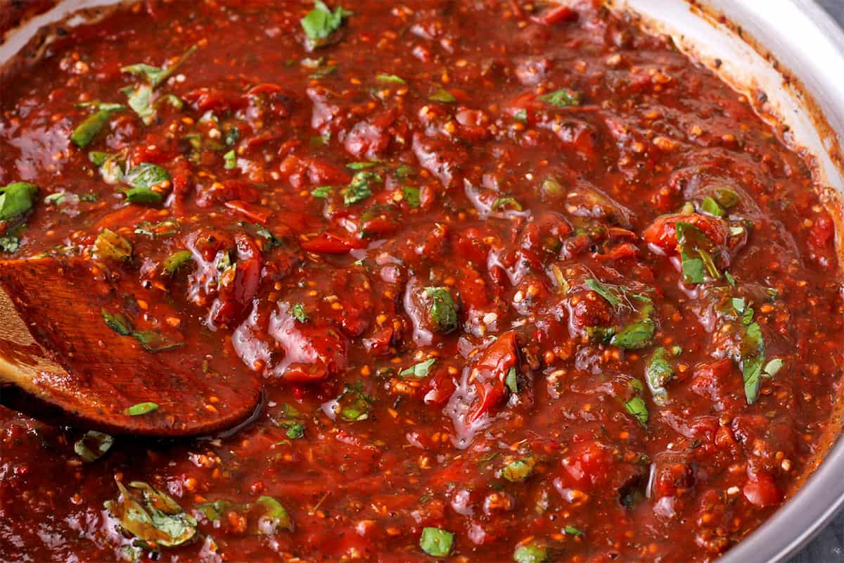 Chopped basil mixed in spicy spaghetti sauce.