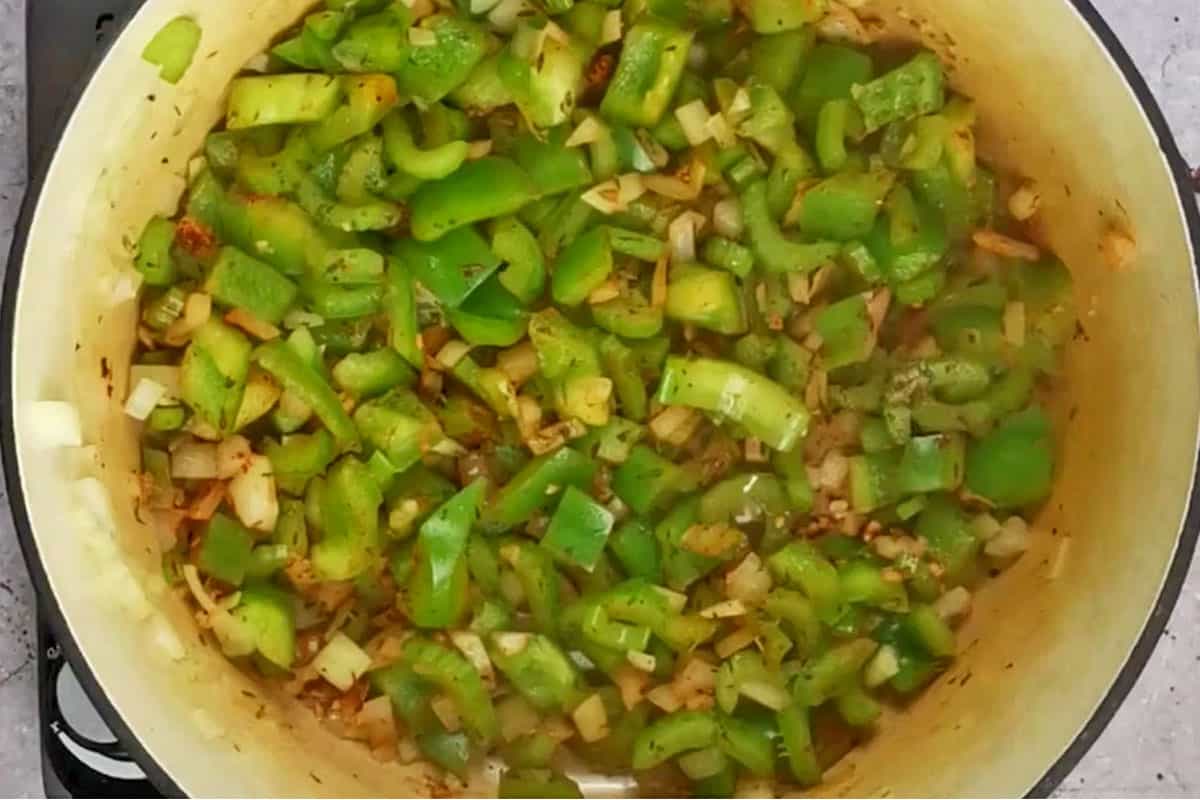 Peppers, onions, celery, garlic and spices in cooking pot.