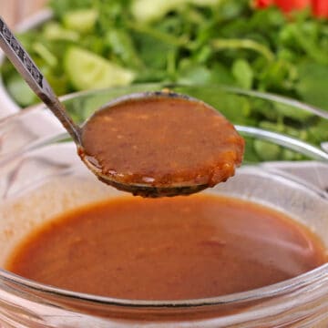 Wasabi vinaigrette dressing in a small ladle over a bowl of dressing.