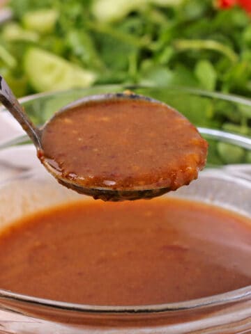 Wasabi vinaigrette dressing in a small ladle over a bowl of dressing.