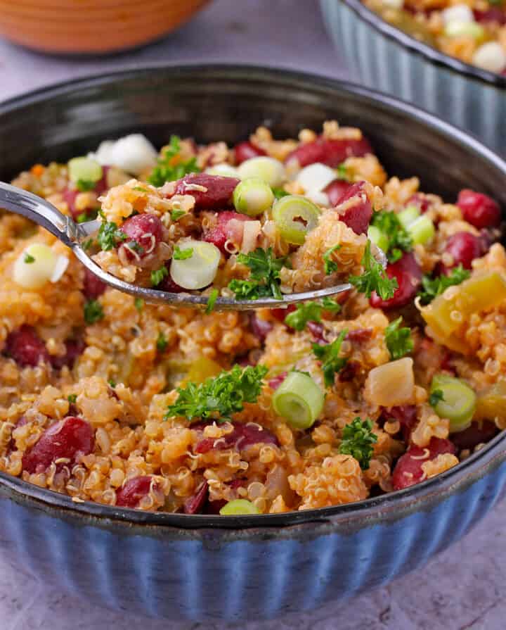 Lifting a spoon of red beans and quinoa over a bowl.