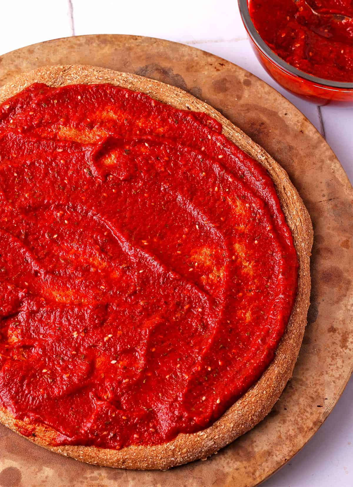 A pizza crust with vegan tomato pizza sauce.