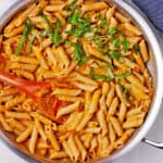 A pan with pasta and chickpea sauce with parsley.