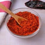 Chipotle seasoning mix in a glass dish with a small wooden spoon.