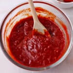 A bowl of huli huli sauce with a wooden spoon.