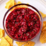 Raspberry salsa in glass bowl with tortilla chips.