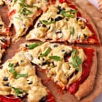 Vegan pizza cheese melted over a pizza with fresh basil, olives, and red onion.