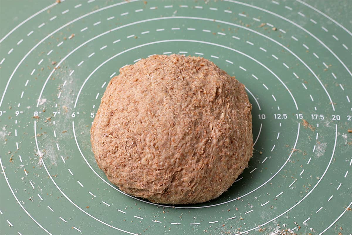 A dough ball made with whole wheat flour on a mat.