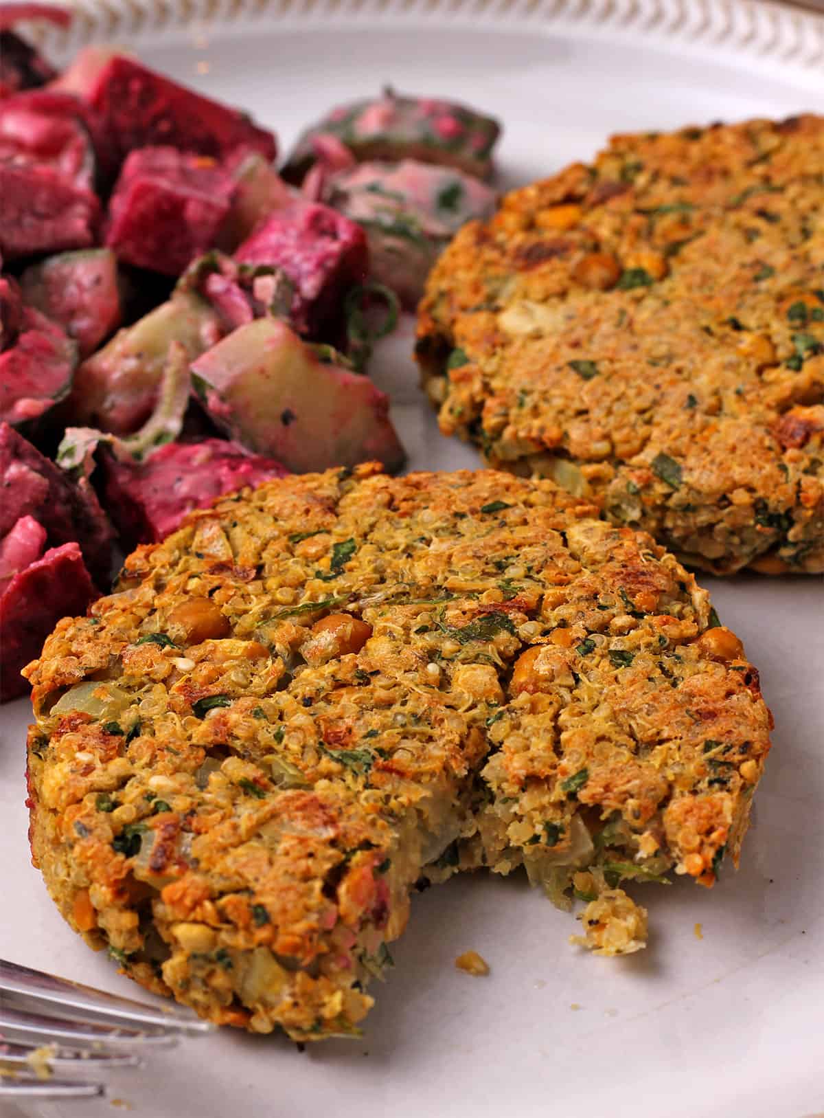 A chickpea patty on a plate is cut with a fork.