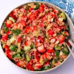 Strawberry cucumber quinoa salad with fresh herbs and almonds in a bowl.