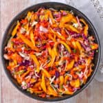 A bowl of mango coleslaw with white and purple cabbage and cilantro.
