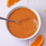 Peanut sauce in a bowl with orange slices beside the bowl.