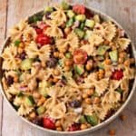 Greek pasta salad with farfalle pasta, tomatoes, cucumbers, red onions, Kalamata olives, and chickpeas.