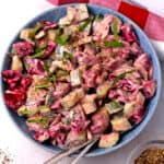 Cucumber beetroot salad with tahini dressing and fresh mint in a bowl with 2 spoons.