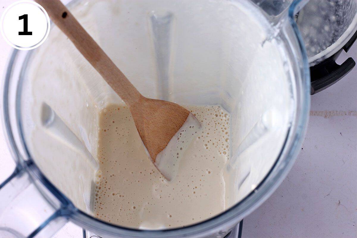 Cashew and pineapple dressing in blender with a wooden spoon.