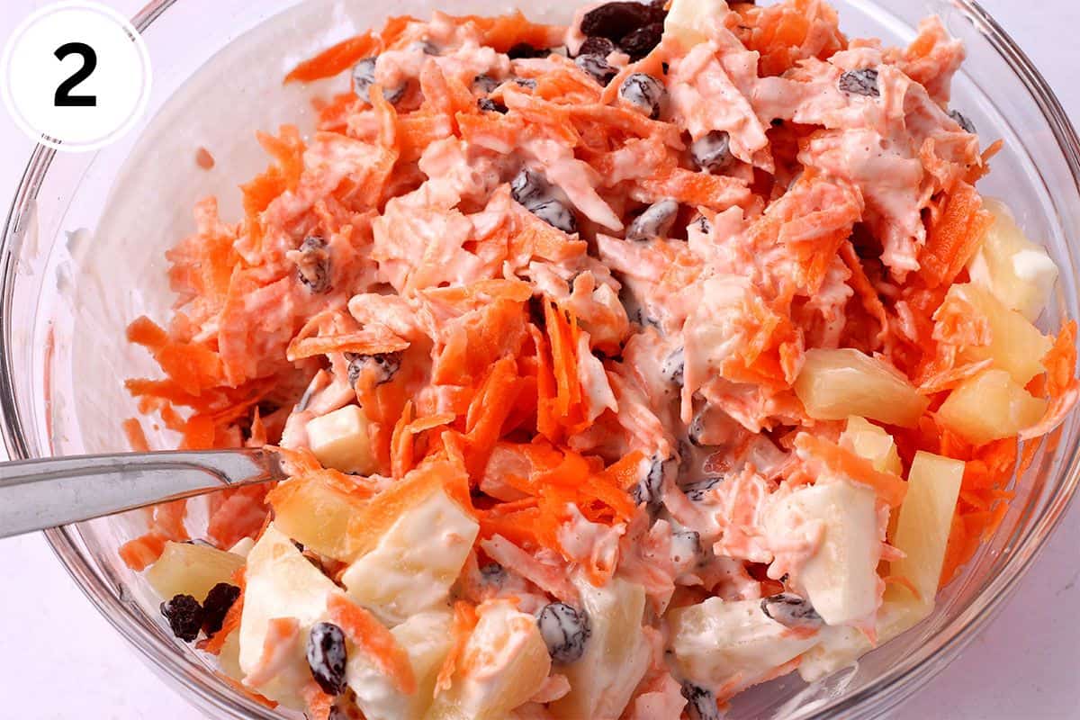 Shredded carrots, pineapple, and raisins are mixed with dressing.