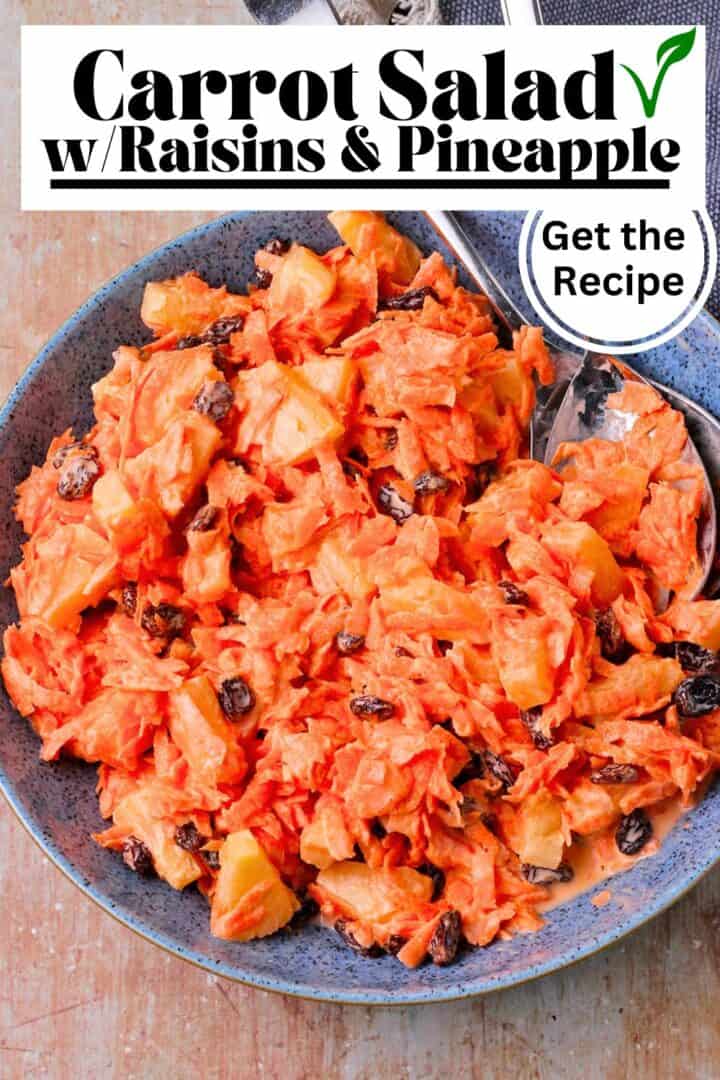 A bowl of carrot salad with raisins, pineapple, and dressing.