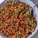 Farro pomegranate salad with pistachios, green onions, and herbs in a blue bowl.