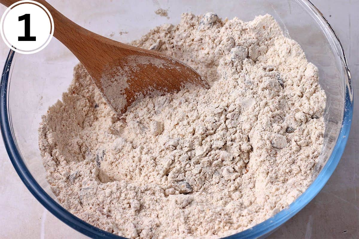 Flour, cranberries, and walnuts are mixed in a bowl.