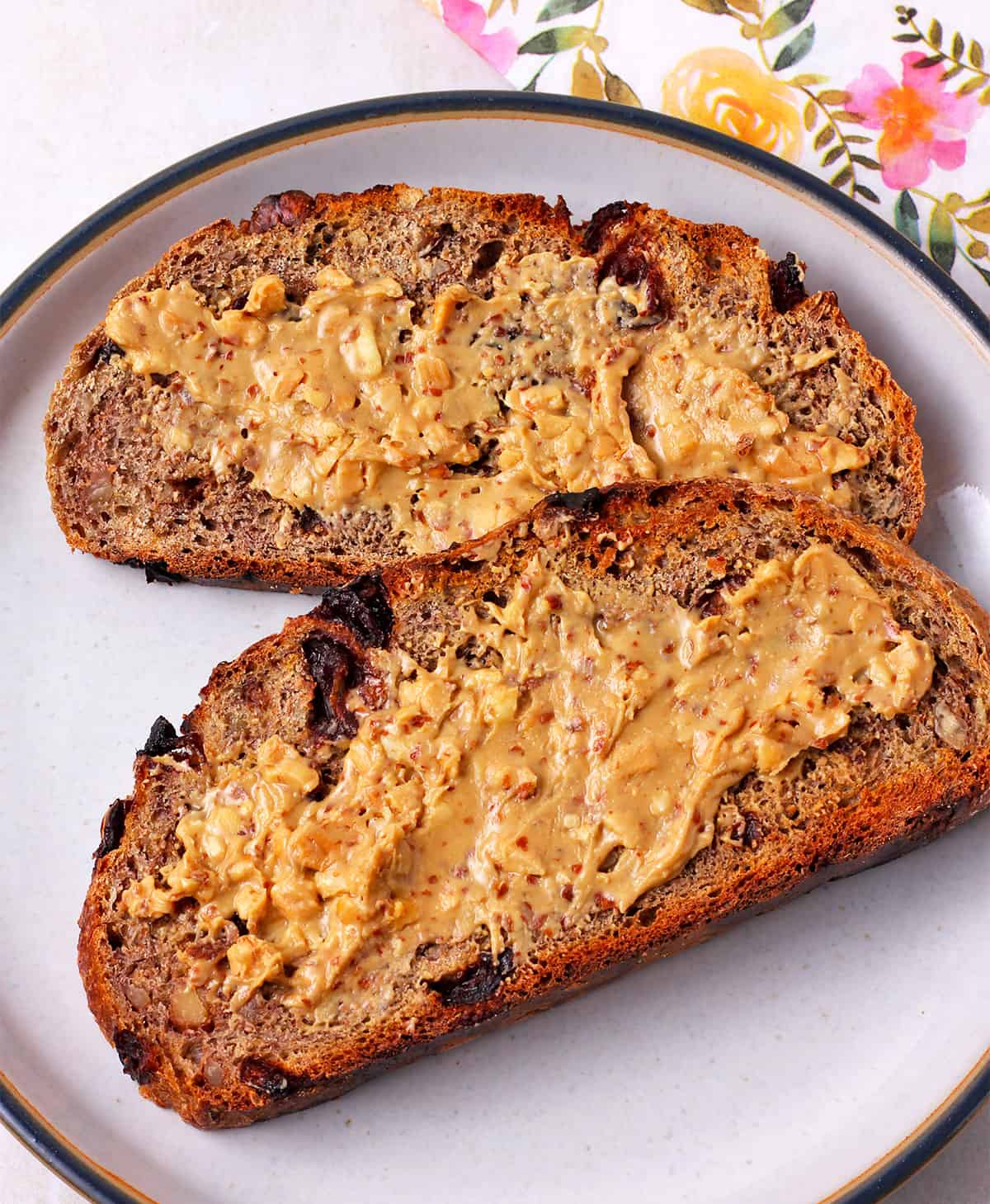 Two slices of cranberry walnut bread with peanut butter.