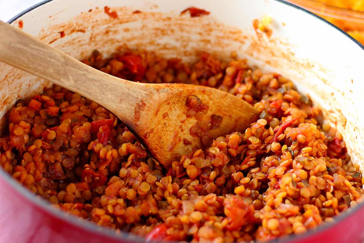 Red lentils with tomatoes are stirred for Shepherds pie filling.