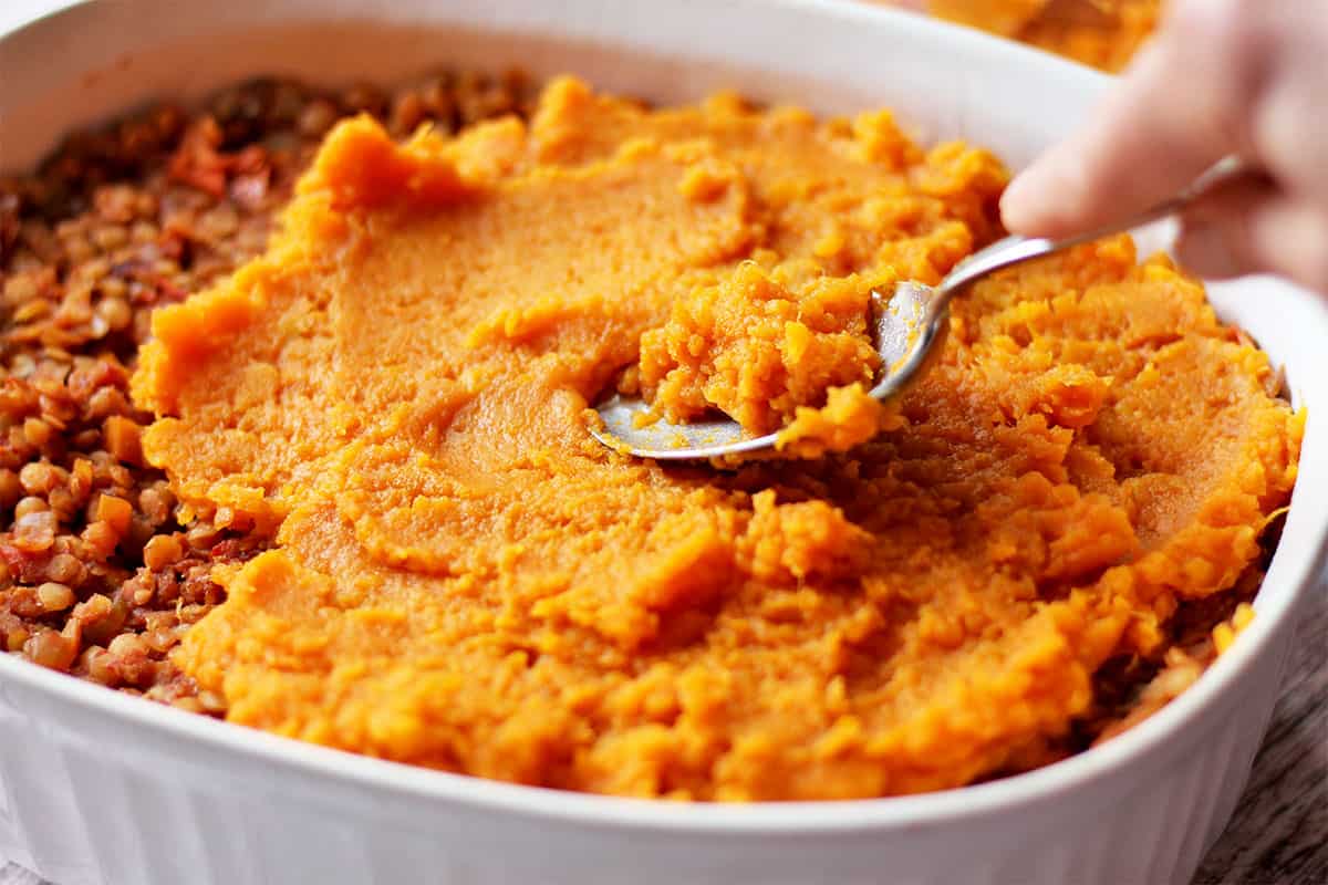 Mashed sweet potatoes are spread over lentil filling.