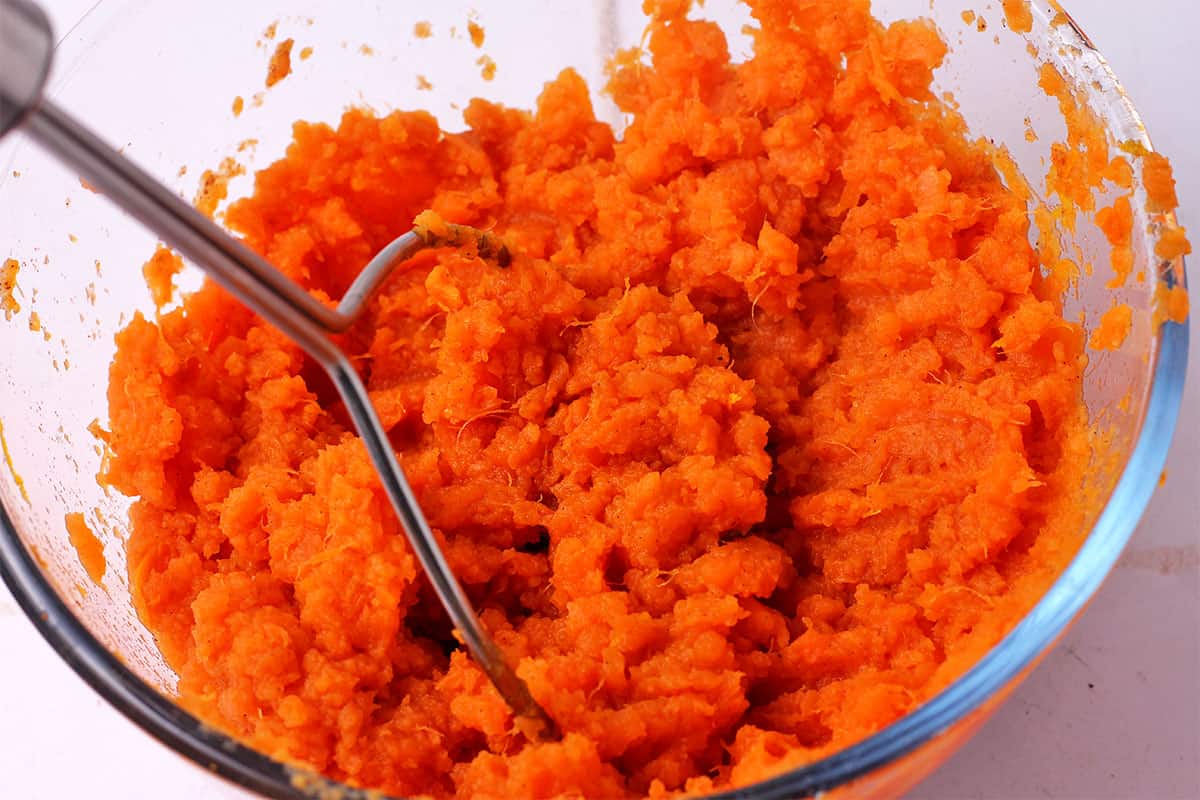 Sweet potatoes are mashed in a bowl.