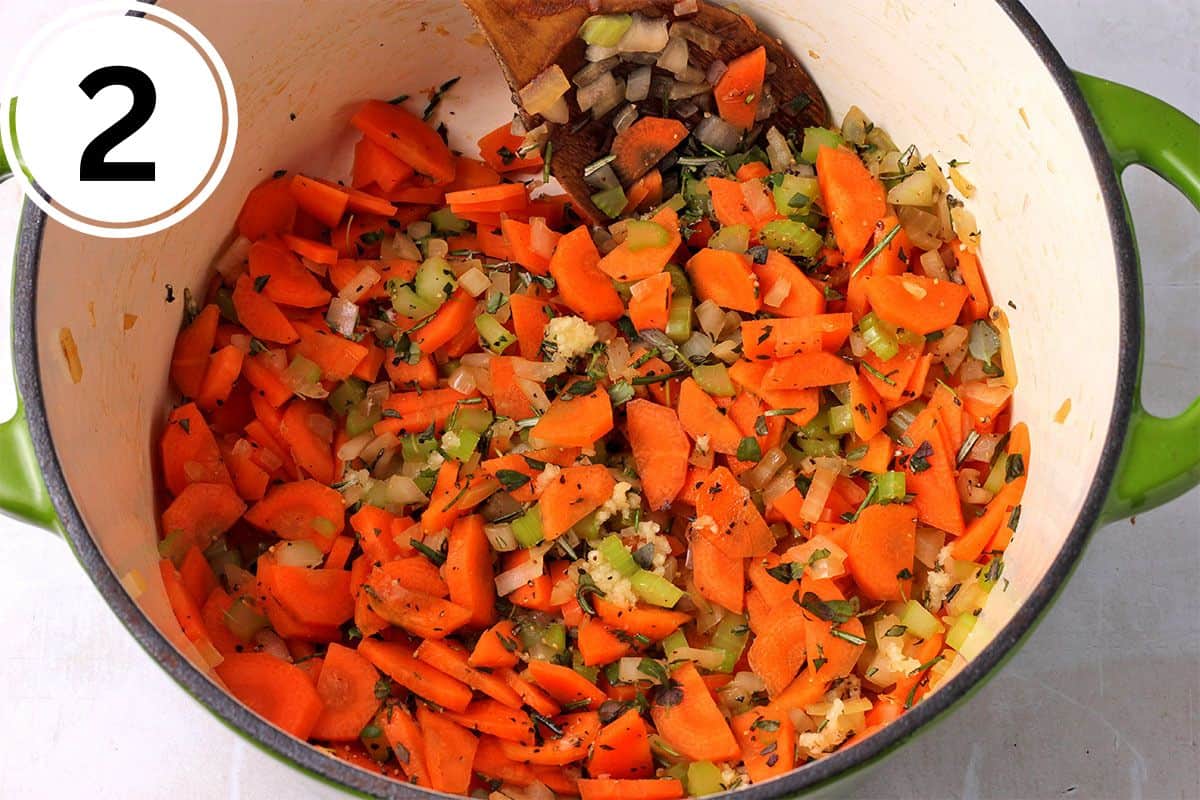 Carrots, onions, celery, garlic, and fresh herbs are cooked in a pot.