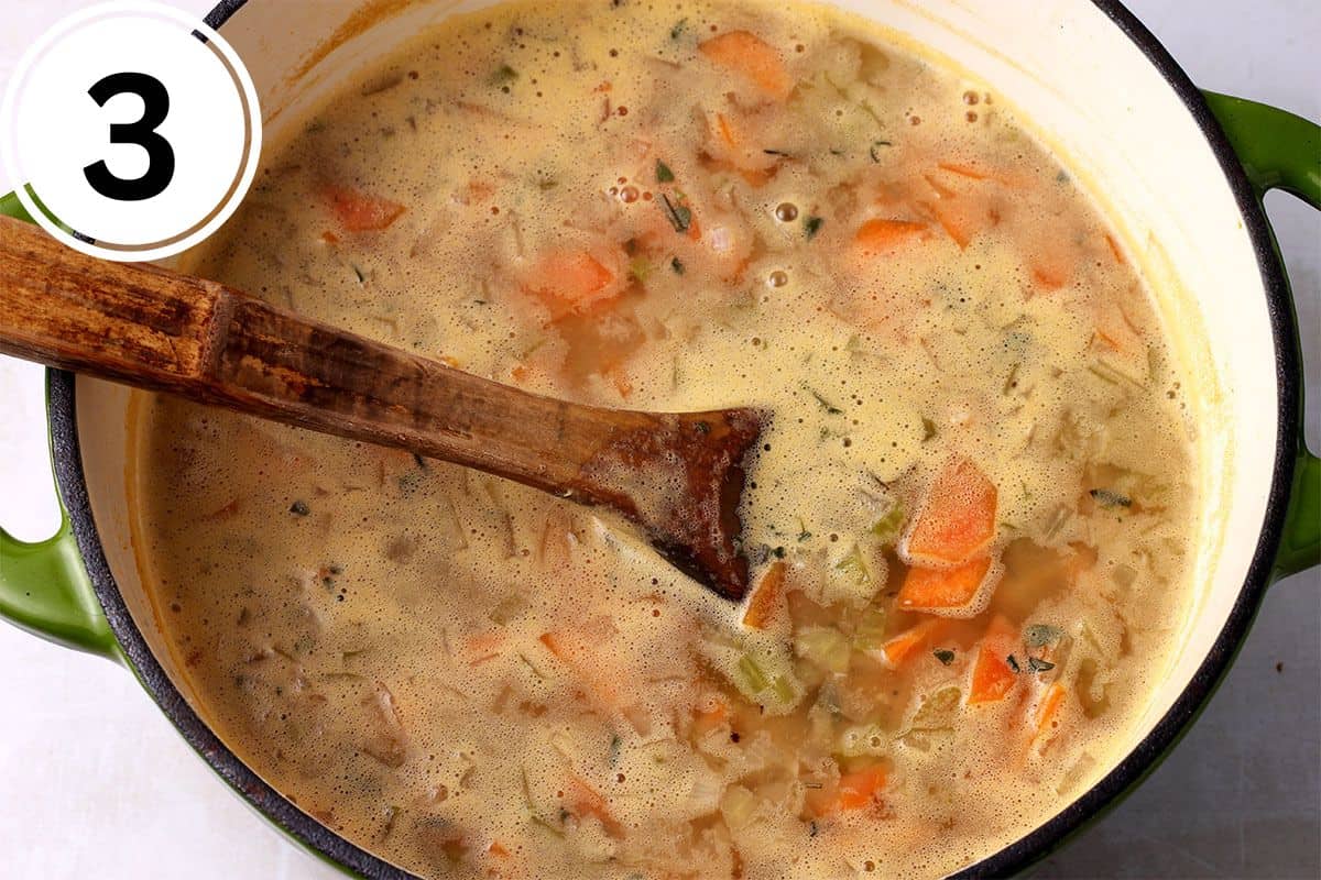 Broth and blended white beans are stirred in a soup pot.